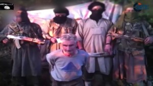 Members of a group calling itself Jund al-Khilafah, or Soldiers of the Caliphate, stand behind French mountaineer Herve Gourdel just before beheading him