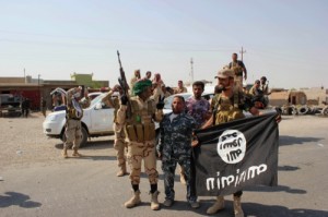 Shiite militiamen hold the flag of the Islamic State group they captured, during an operation in Iraq