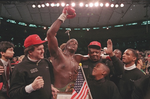 Heavyweight boxer James “Buster” Douglas waves his gloved hand to the cheering crowd as he makes his way to the dressing room following a 10th round knockout victory over Mike Tyson