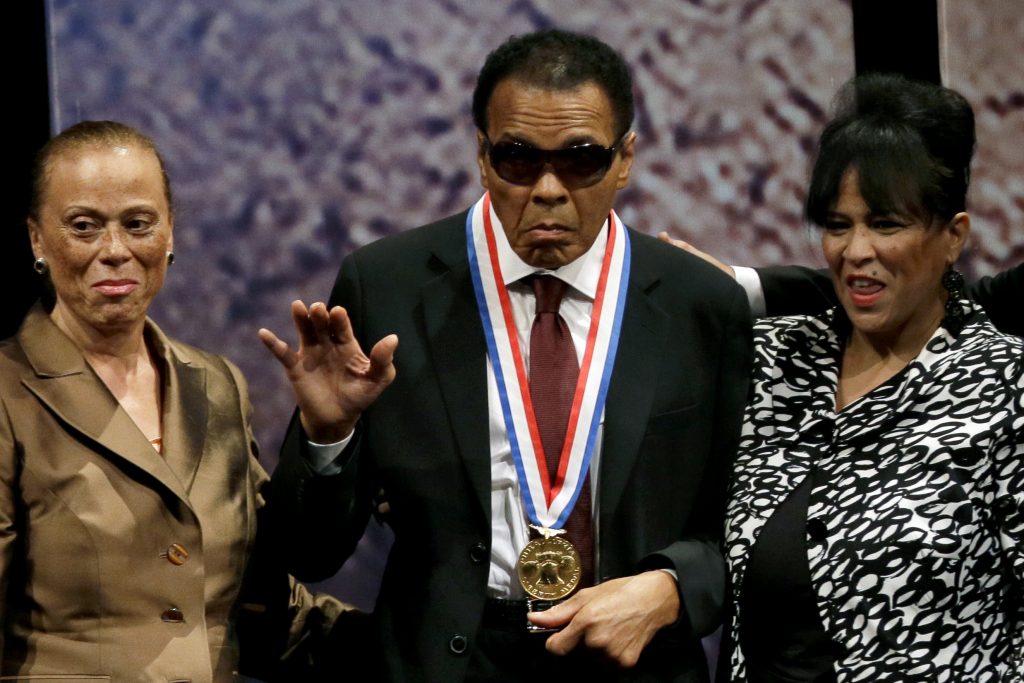 FILE - In this Sept. 13, 2012, file photo, retired boxing champion Muhammad Ali, center, waves alongside his wife Lonnie Ali, left, and his sister-in-law Marilyn Williams, right, after receiving the Liberty Medal during a ceremony at the National Constitution Center in Philadelphia. Ali, the magnificent heavyweight champion whose fast fists and irrepressible personality transcended sports and captivated the world, has died according to a statement released by his family Friday, June 3, 2016. He was 74. (AP Photo/Matt Slocum, File)